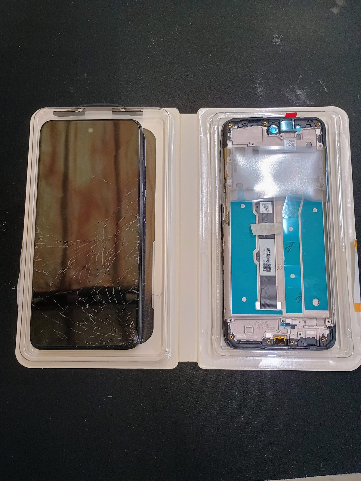 Damaged Moto G 5G beside the empty replacement display and frame assembly.